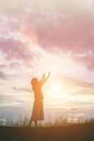 silueta de mujer rezando sobre un hermoso cielo de fondo foto