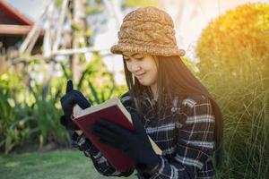 chica encantadora hipster relajándose en el parque mientras lee un libro, disfruta de la naturaleza. foto