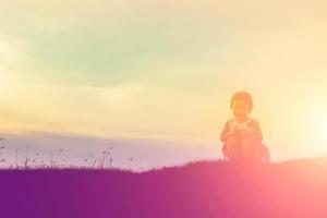 silueta de niño, momentos de alegría del niño. en la puesta de sol de la naturaleza foto