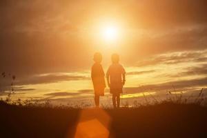 silueta de niños felices y puesta de sol feliz foto