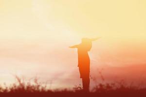 silueta de niño, momentos de alegría del niño. en la puesta de sol de la naturaleza foto