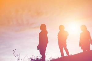 silueta de niños felices y puesta de sol feliz foto