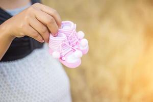 Pregnant woman holding baby shoes photo