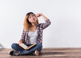 Young hipster woman holding books and pointing up on isolated white background. photo