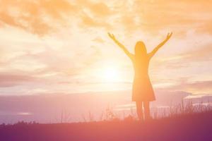Silhouette of woman praying over beautiful sky background photo