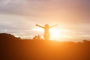 Silhouette of woman praying over beautiful sky background photo