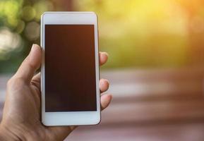 Hand holding white mobile phone on vintage weave wood table photo