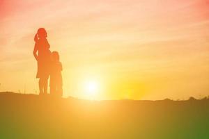 Mother encouraged her daughter out of the shadows at sunset. photo