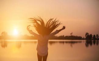 Silhouette of the beautiful girl in the nature at summer sunset. photo