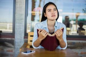 chica encantadora hipster relajándose en el parque mientras lee un libro, disfruta de la naturaleza. foto