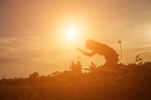 Silhouette of woman praying over beautiful sky background photo