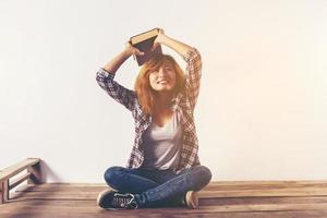 Young hipster woman holding books and pointing up on isolated white background. photo