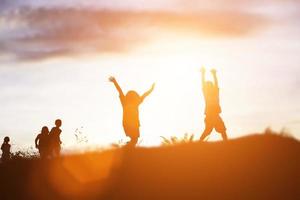 silueta de niños felices y puesta de sol feliz foto