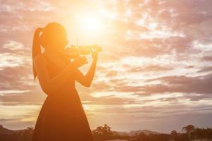 mujer joven tocando el violín con montañas en el fondo foto