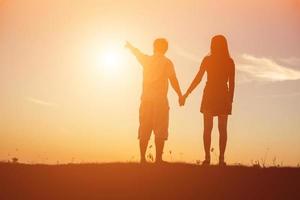 silhouette of a man and woman holding hands with each other, walking together. photo