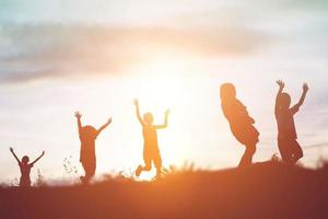 silueta de niños felices y puesta de sol feliz foto