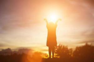 silueta de niño, momentos de alegría del niño. en la puesta de sol de la naturaleza foto