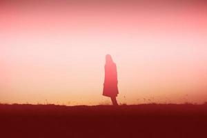 silhouette of a young woman standing alone photo