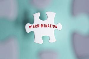 Discrimination word on puzzle pieces isolated on blurred background. photo