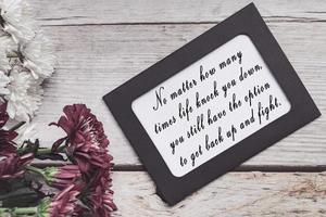 Motivational quote on chalkboard frame and white flowers on on wooden desk. photo