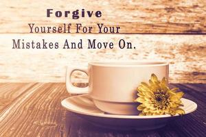 Motivational quote with coffee cup and flowers on wooden table. photo