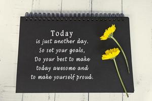 Motivational and inspirational quote on black note book with sunflowers. photo