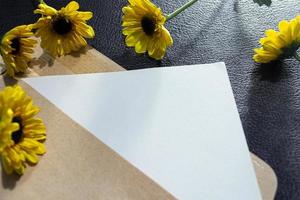 Paper and envelope on wooden surface with sunflowers flat lay with copy space. photo