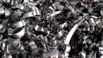 Steel scrap materials recycling. Aluminum chip waste after machining metal parts on a cnc lathe. Closeup twisted spiral steel shavings. Small roughness sharpness, possible granularity, blurred focus video