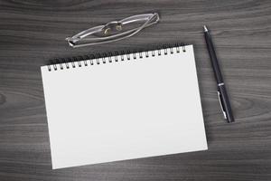 Directly above view of office wooden table with pen, notepad and reading glasses photo