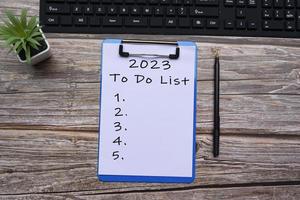 2023 To do list text on blue clipboard on wooden desk. Resolutions concept. photo