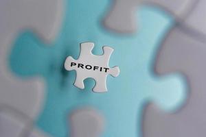 Profit word on puzzle pieces isolated on blue background. Business concept. photo