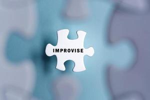 Improvise word on puzzle pieces isolated on blurred blue background. photo