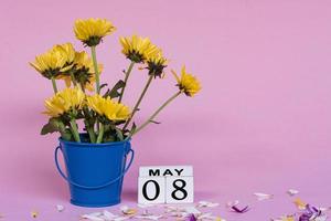 Yellow dahlia flower with wooden block cube on pink background. Copy space. photo