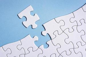 Piece of jigsaw puzzle on blue paper. Directly above. Copy space. photo