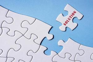 White jigsaw puzzle with word solution over blue background. photo