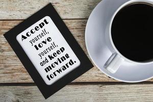 Motivational and inspirational quotes on chalkboard with coffee cup on wooden desk photo