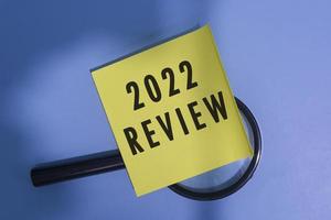 2022 Review on Adhesive Note With Magnifying Glass Against Blue background. photo