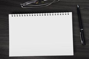 Directly above view of office wooden table with pen, notepad and reading glasses photo