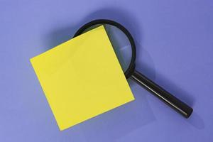Adhesive Note With Magnifying Glass Against Purple background. Copy Space. photo