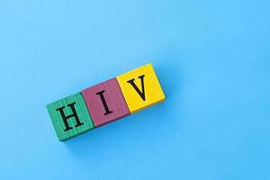 HIV Human Immunodeficiency Virus acronym on colorful wooden cubes against blue background. Flat lay. Copy Space. Directly above. photo