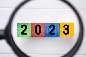 2023 number on colorful wooden cube with magnifying glass. New year concept. photo