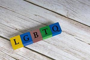 LGBTQ acronym on colorful wooden cubes against blue background. photo