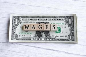 Wages word written on wood block with American Dollar-bills. Directly above. photo