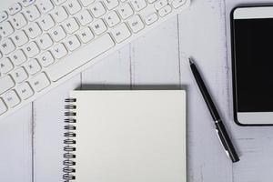 Directly above view of a desk table with keyboard, pen, notepad and smartphone. photo