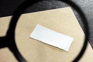 Paper and envelope on wooden surface with magnifying glass. Copy space. Flat lay photo