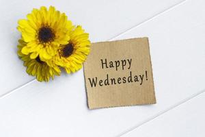 Happy Wednesday text on torn brown paper on white wooden table. photo