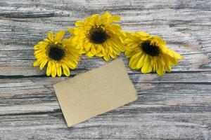 Torn brown paper on wooden surface and sunflower flat lay with copy space. photo