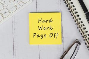Hard Work Pays Off word is written on the adhesive note. photo