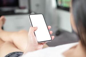 maqueta de teléfono en mano de mujer que muestra una pantalla blanca en casa, tomada desde la vista trasera, concepto mínimo foto