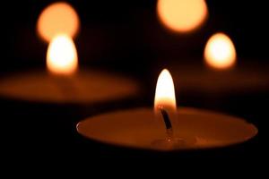 Cup candles that are lit in the dark, holy light,Burning candles on dark surface. Memory day